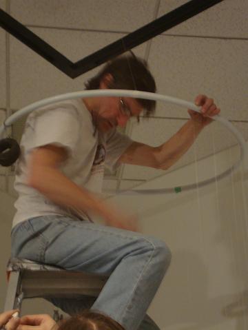 install - beadology (9).JPG - Scott Price - gallery staff on the top of a very large ladder starting to attach the strands